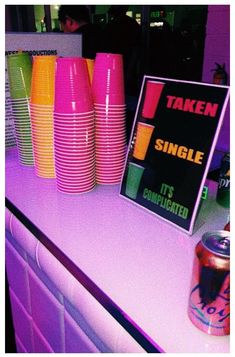 there is a table with neon colored cups on it and a sign that says taken single