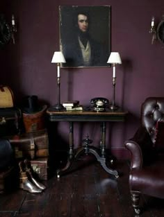 an old fashioned desk and chair in a room with purple walls, wooden floors and leather furniture