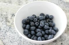 a white bowl filled with blueberries on top of a counter