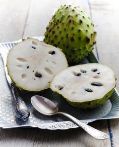 two pieces of fruit on a plate with spoons