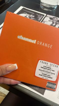 a hand holding an orange box with the name frank ocean on it