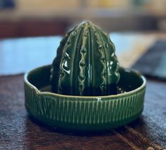 a small cactus in a green bowl on a table