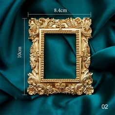 a gold frame sitting on top of a green satin fabric with measurements for it to be framed