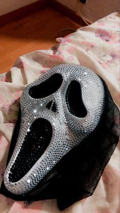 a black and silver mask sitting on top of a bed