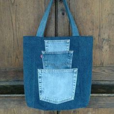 a blue jean bag hanging on a wooden door with the back pocket open and two small pockets in it