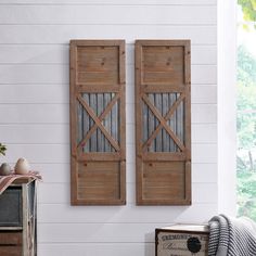 two wooden shutters mounted to the side of a white wall next to a suitcase