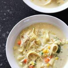 two bowls filled with pasta and vegetables on top of a black table next to each other