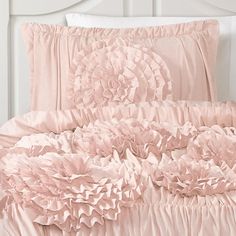 a bed with pink ruffled sheets and pillows