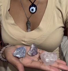 a woman is holding some rocks in her hand with an evil eye charm on it