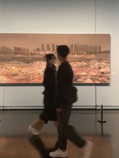 two people are walking in front of a large cityscape that is on display