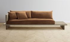 a couch sitting on top of a wooden table in front of a wall with two pillows