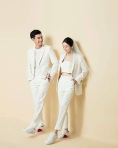 two people standing next to each other in white outfits