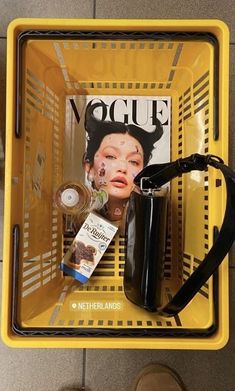 a yellow basket with some items on top of it and a magazine in the middle