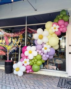 a bunch of balloons that are in front of a store window with flowers on it