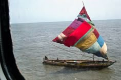 a colorful sail boat floating on top of the ocean