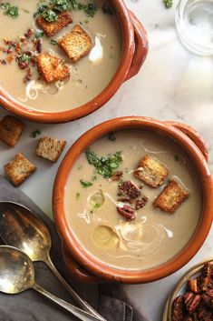 two brown bowls filled with soup and croutons