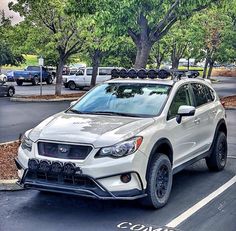 a white subarunt is parked on the side of the road in front of some trees