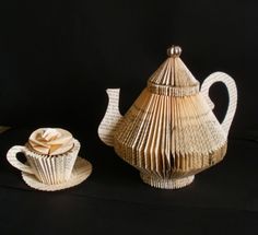 a tea pot and cupcakes made out of book pages on a black background