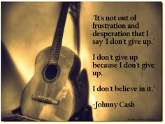 a guitar sitting on top of a table next to a wall with a quote from johnny cash