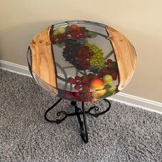 a glass table with fruit on it in the middle of a carpeted floor next to a wall