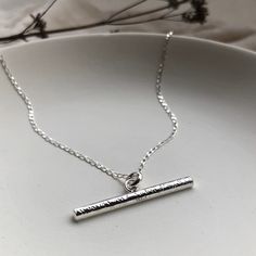 "The Luna T Bar Necklace is a modern twist on a classic jewellery piece. As with all my jewellery it has been handcrafted, with love, in small batches from my Brighton workshop. This necklace is made using recycled sterling silver and comes on an 18\" fine diamond cut curb chain. The T bar measures approximately 3cm from end to end and is 3mm thick. This necklace is perfect for everyday wear as a stand alone piece and also looks great layered up with other necklaces. The textured surface is particularly striking when the light catches it giving it a lovely shimmering appearance. The perfect gift for someone special, whether that's you or a loved one. All of my jewellery comes wrapped in recycled and 100% recyclable white pillow boxes and colourful recycled tissue. All of my packaging is 10 Minimalist Sterling Silver Bar Necklace With Rectangular Pendant, Minimalist Silver Engraved Bar Necklace, Classic Sterling Silver Bar Necklace, Minimalist Engraved Silver Bar Necklace, Dainty Sterling Silver Bar Necklace For Everyday, Simple Sterling Silver Necklace With Rectangular Pendant, Minimalist Silver Necklace, Bar Pendants, Textured Wedding Band