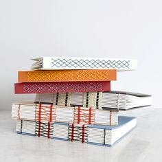 four books stacked on top of each other in different colors and patterns, with one being folded