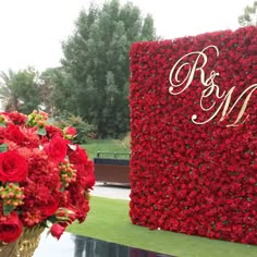 red flowers are in a vase next to a wall with the initials r and m