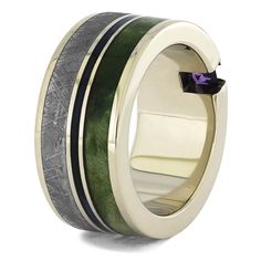 This amazing men's wedding band features a trio of unique materials and a princess cut gemstone. You'll see it here with a tiny, purple amethyst, but this alternative ring can be customized to feature a different square stone, if desired. Green box elder burl wood is bisected by the channel set stone. Meteorite is inlaid on the other side of the center pinstripe of blue burl wood. RING LAYOUTRing Width: 10 mm Ring Sleeve: 14k White GoldRing Profile: FlatRing Finish: Polished1 mm 14k White Gold3 Alternative Ring, Amethyst Wedding Rings, Channel Set Rings, Gibeon Meteorite, Meteorite Jewelry, Unique Mens Rings, Jewelry By Johan, Amethyst Wedding, Box Elder