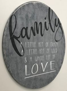 a round wooden sign with the words family and a little bit of crazy on it