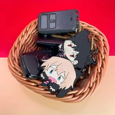 two cell phones sitting on top of each other in a basket next to some keys