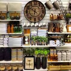 a large clock mounted to the side of a wall next to shelves filled with pots and pans