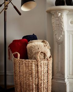 a basket filled with blankets sitting next to a lamp and floor lamp in a room