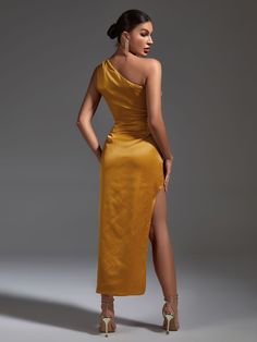 a woman in a yellow dress with one leg slited up and her hand on her hip