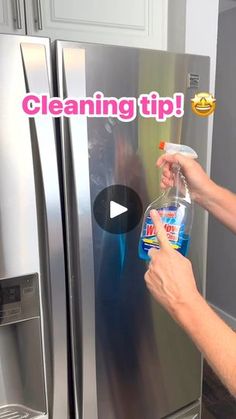 someone is cleaning their stainless steel refrigerator with dishwasher deterant and vinegar bottle