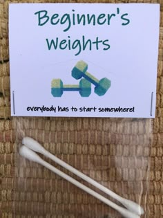 two white toothbrushes sitting on top of a brown carpet next to a sign that says beginner's weights