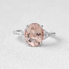 an oval morganite and diamond ring on a white surface