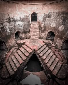 an old building with steps leading up to the top and bottom floor, in which there is water below