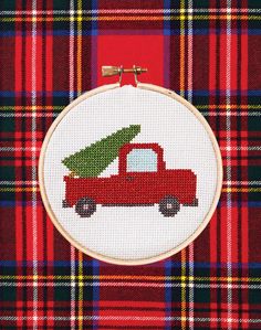 a red truck with a christmas tree on it's back in front of a plaid background