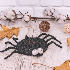 a crocheted spider sitting on top of a wooden floor next to cotton balls