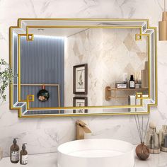 a bathroom with a sink, mirror and shelves on the wall above it is decorated in gold trim