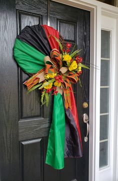 a colorful wreath on the front door of a house that is decorated with flowers and ribbons