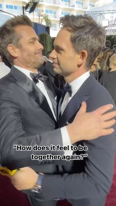 two men in suits hugging each other on the red carpet at an oscars event