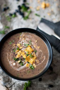 a black bowl filled with soup on top of a table