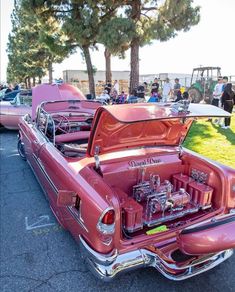 an old pink car with its hood open