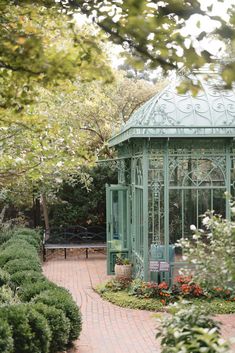 a green gazebo surrounded by greenery and flowers