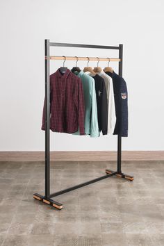 clothes hanging on rail in room with tile flooring and white wall behind the garment rack