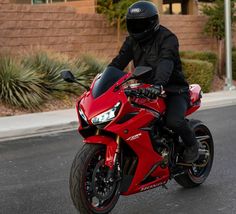 a man riding on the back of a red motorcycle