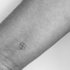 a small four leaf clover tattoo on the left inner arm, with an arrow at the center