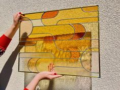 a woman is holding up a stained glass window with her hand on the side of it