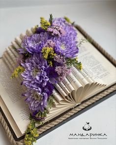 a bouquet of purple flowers sitting on top of an open book